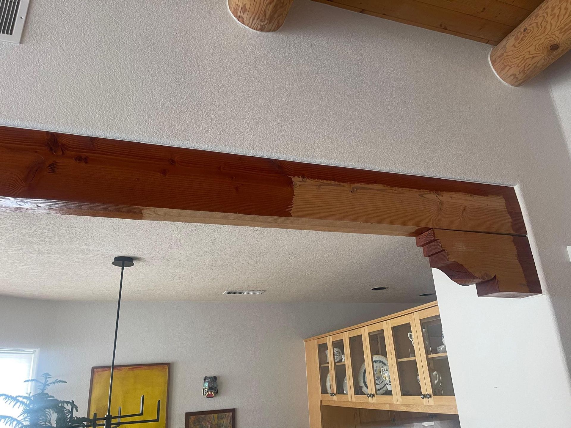 Interior room with exposed wooden beams, white ceiling, and a loft railing above a doorway.