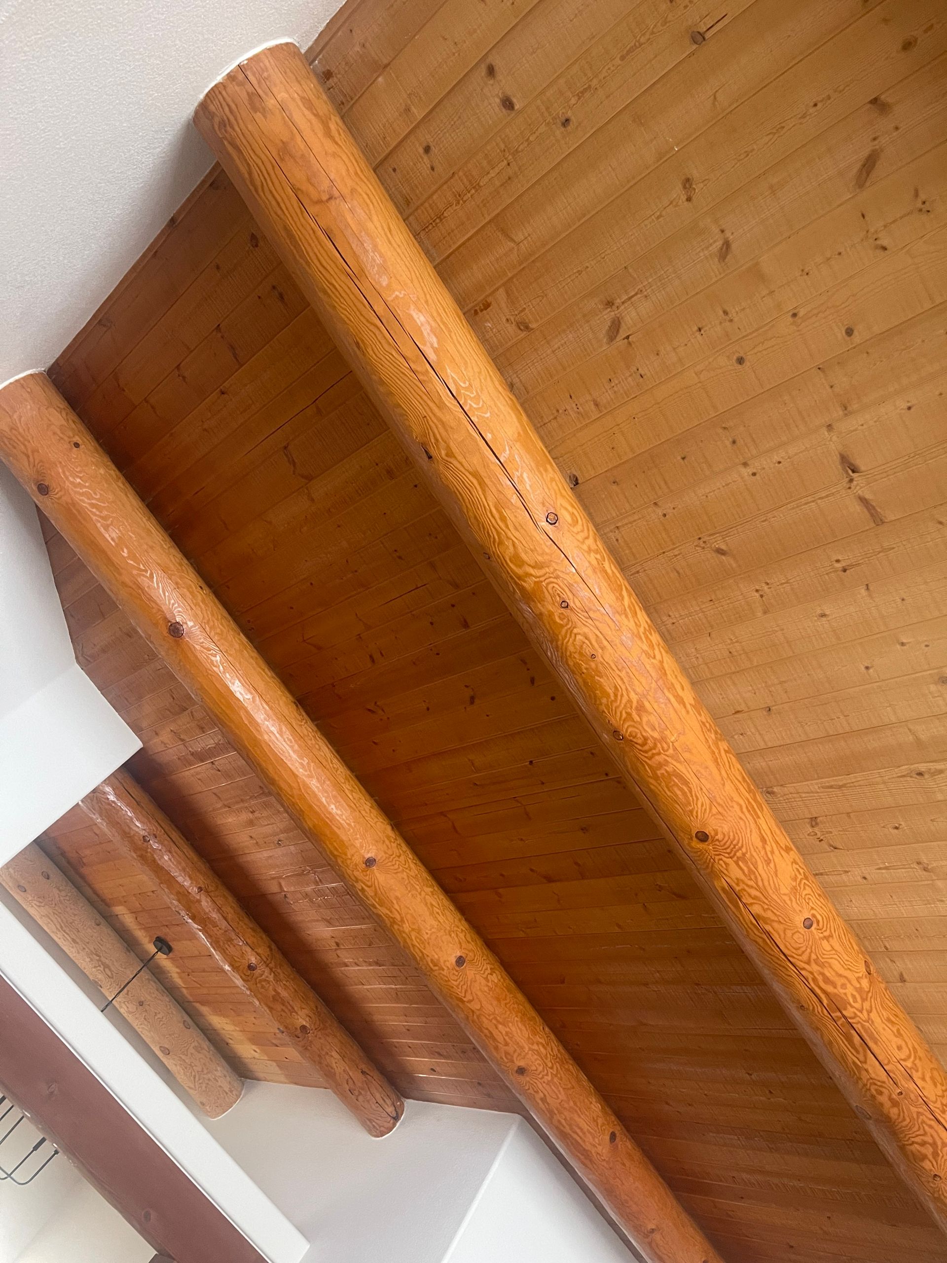 Close-up of a wooden staircase underside with honey-colored railings and slanted steps.