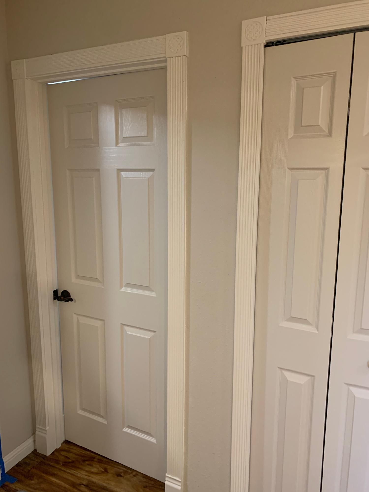 Two white paneled closet doors in a beige room with hardwood floors