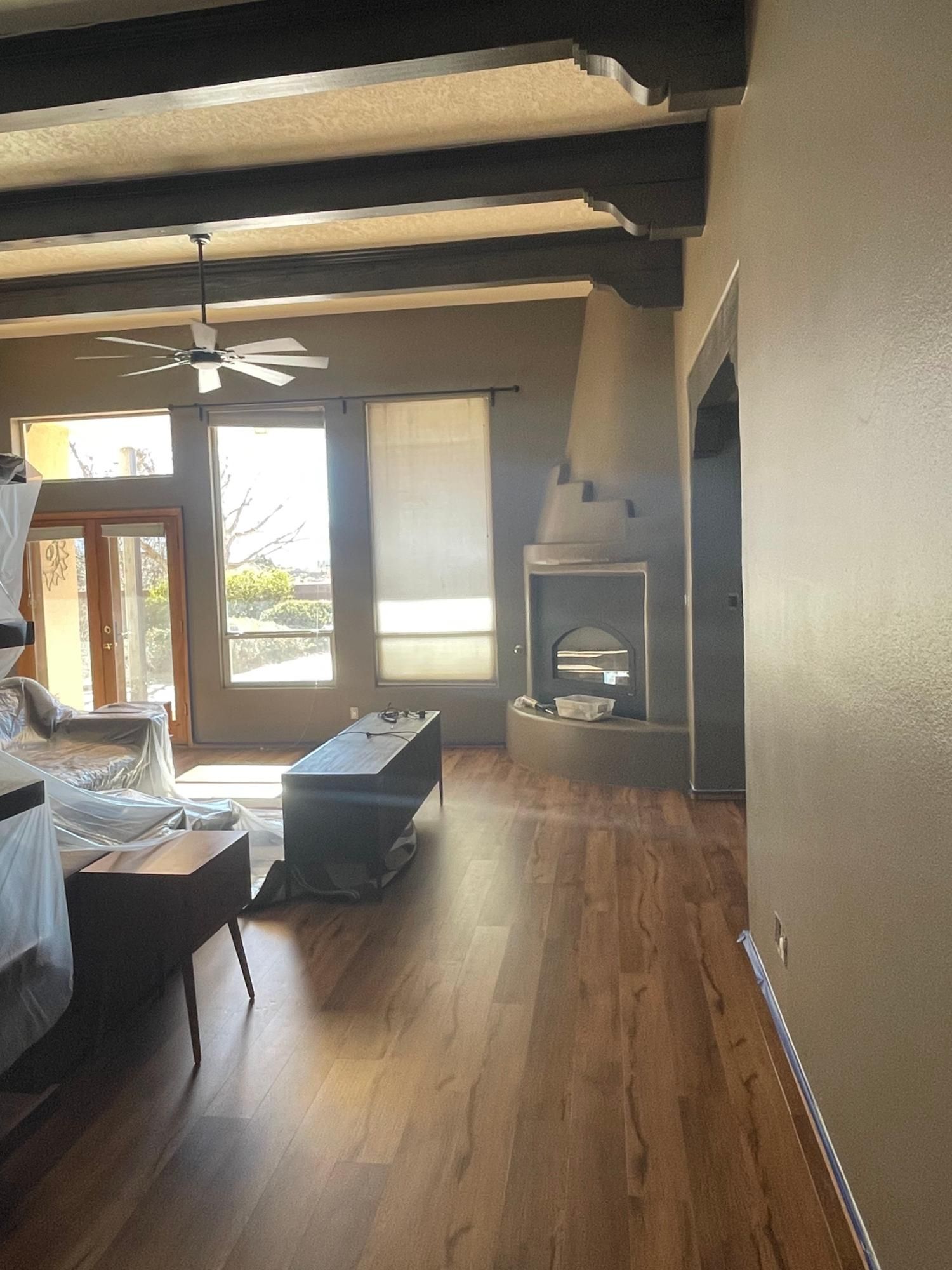 Living room with vaulted ceiling, fireplace, wooden floors, and large windows letting in daylight