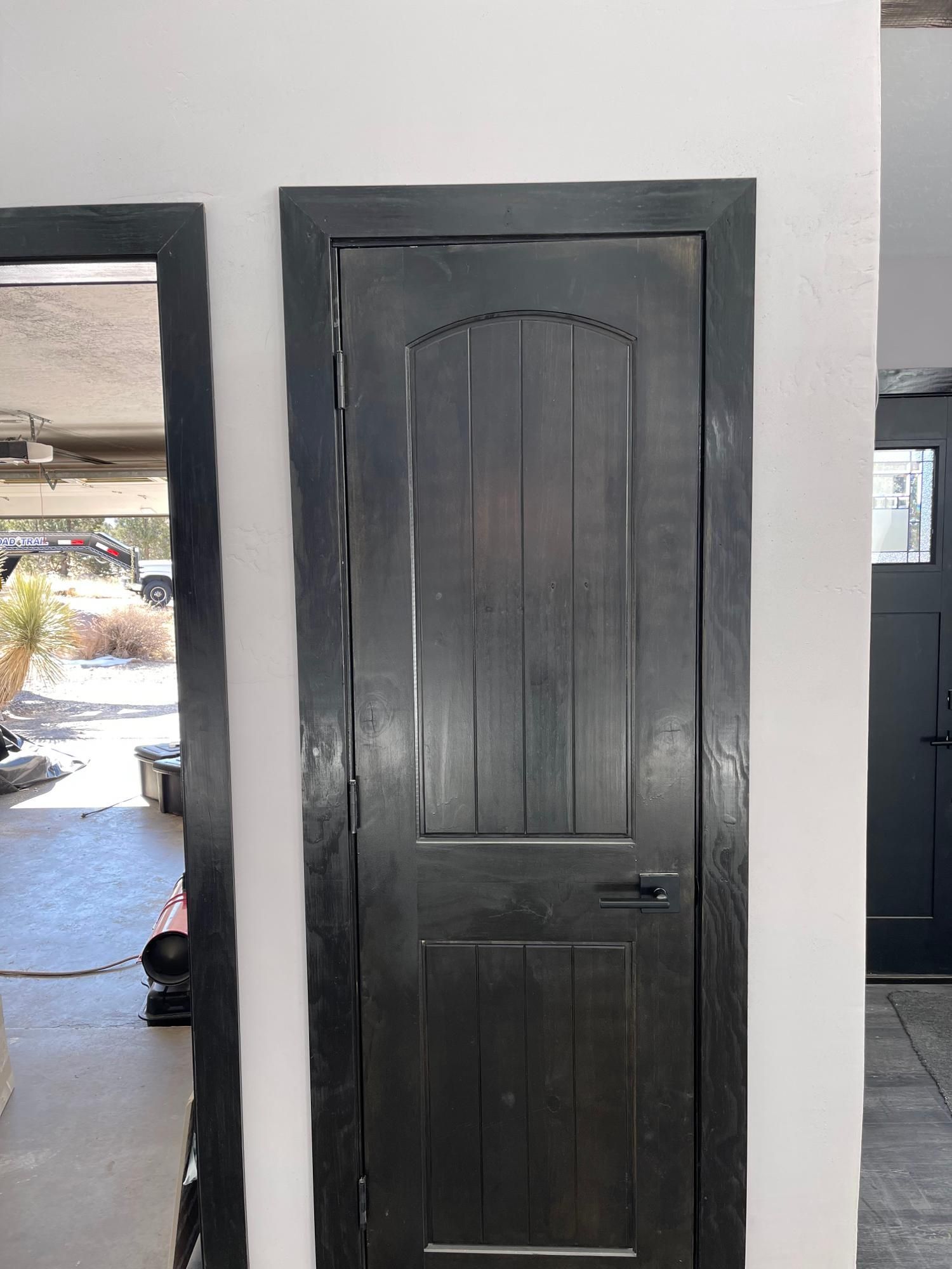 Black paneled door in a white-walled interior hallway