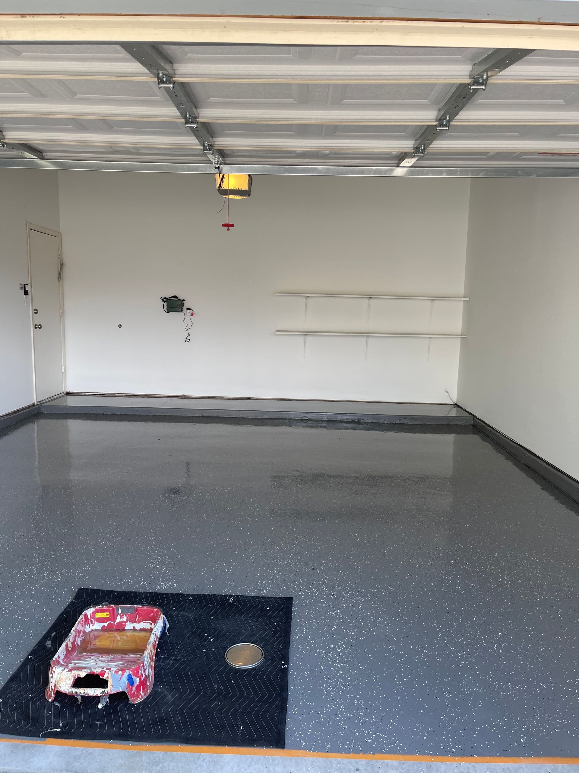 Empty garage with speckled gray floor, white walls, and a closed overhead door.