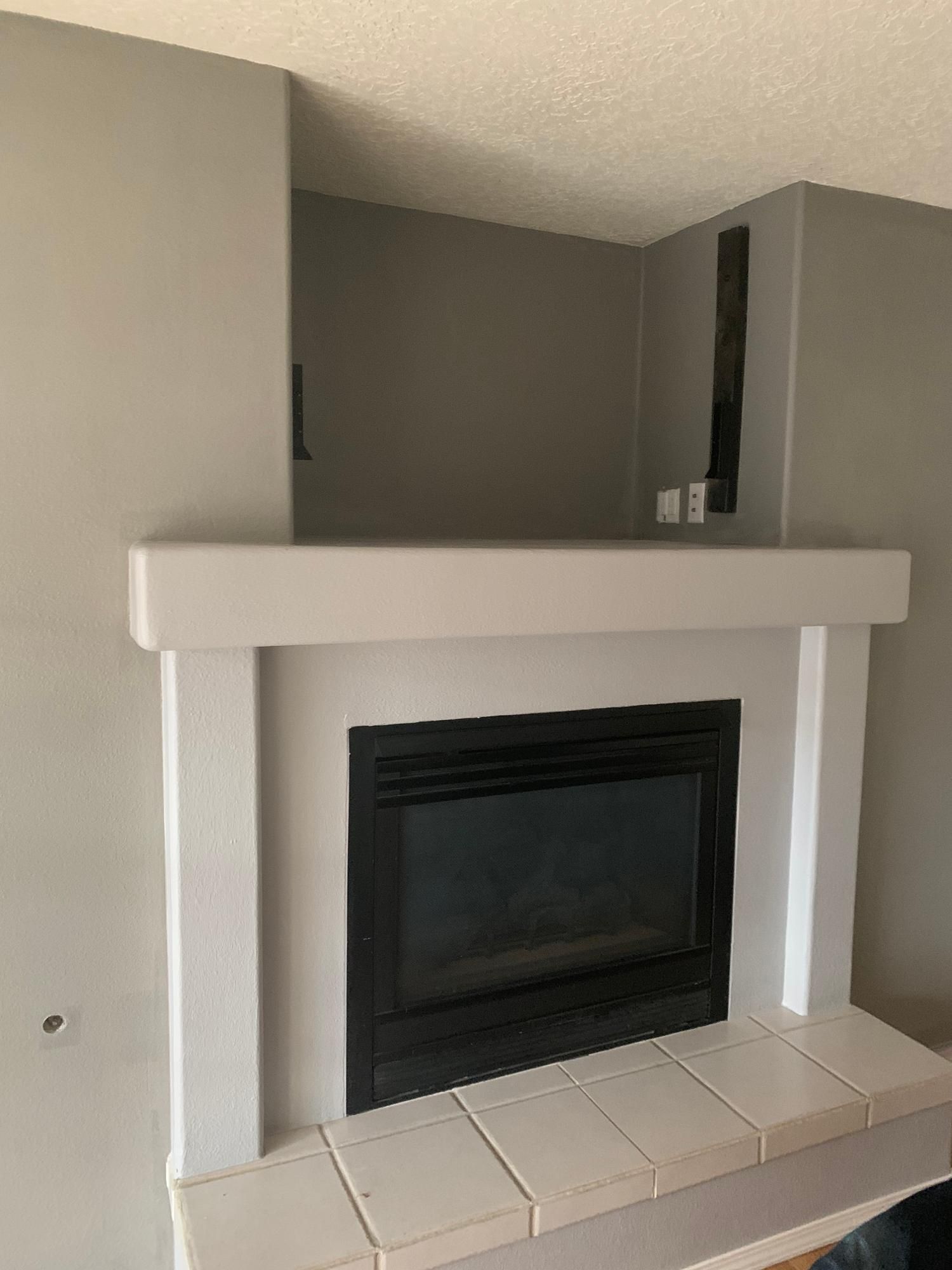 Modern white fireplace with black insert and tiled hearth in a gray room