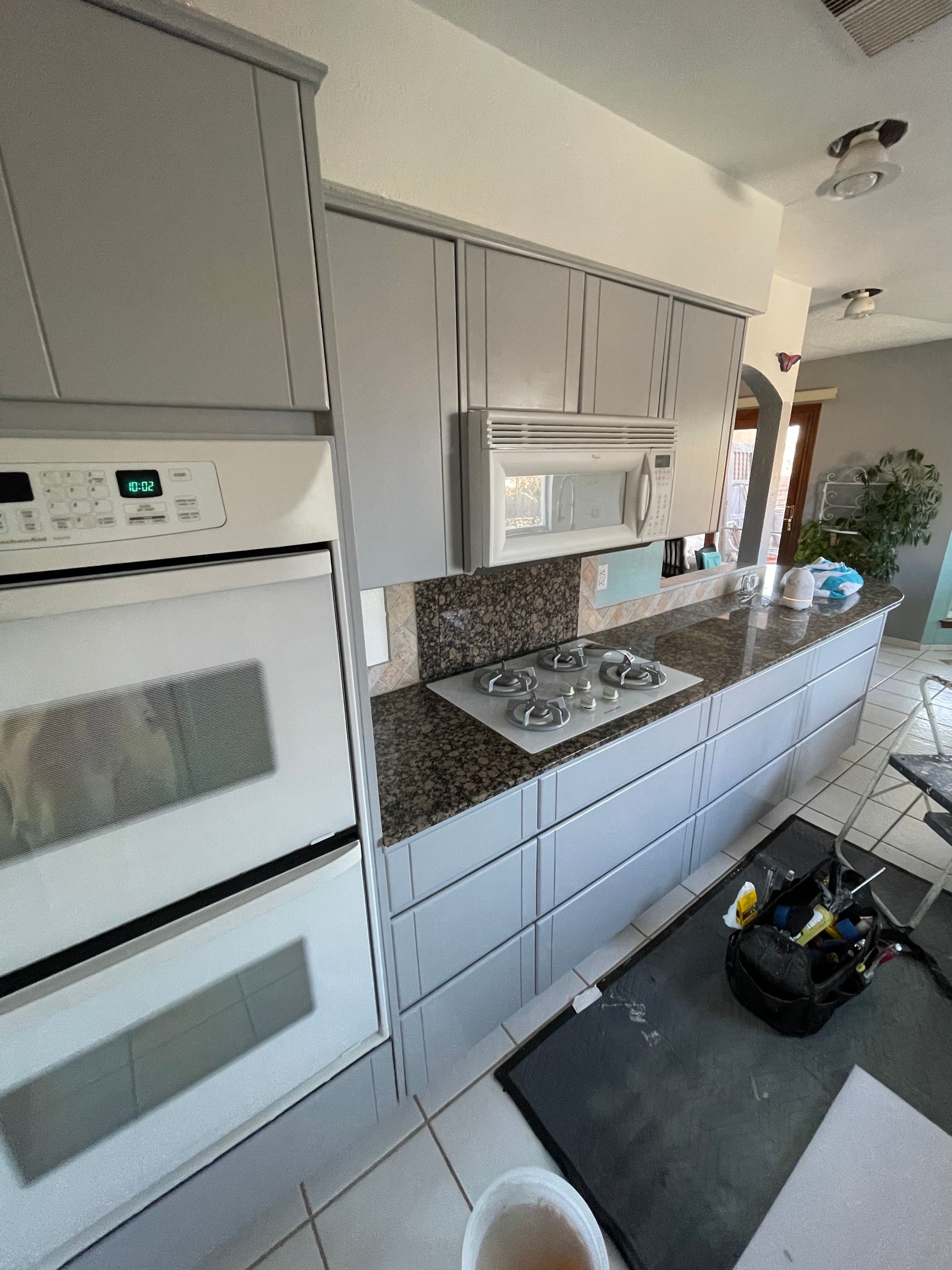 Modern kitchen with white cabinets, built-in oven and microwave, gas cooktop, and countertop with cleaning tools