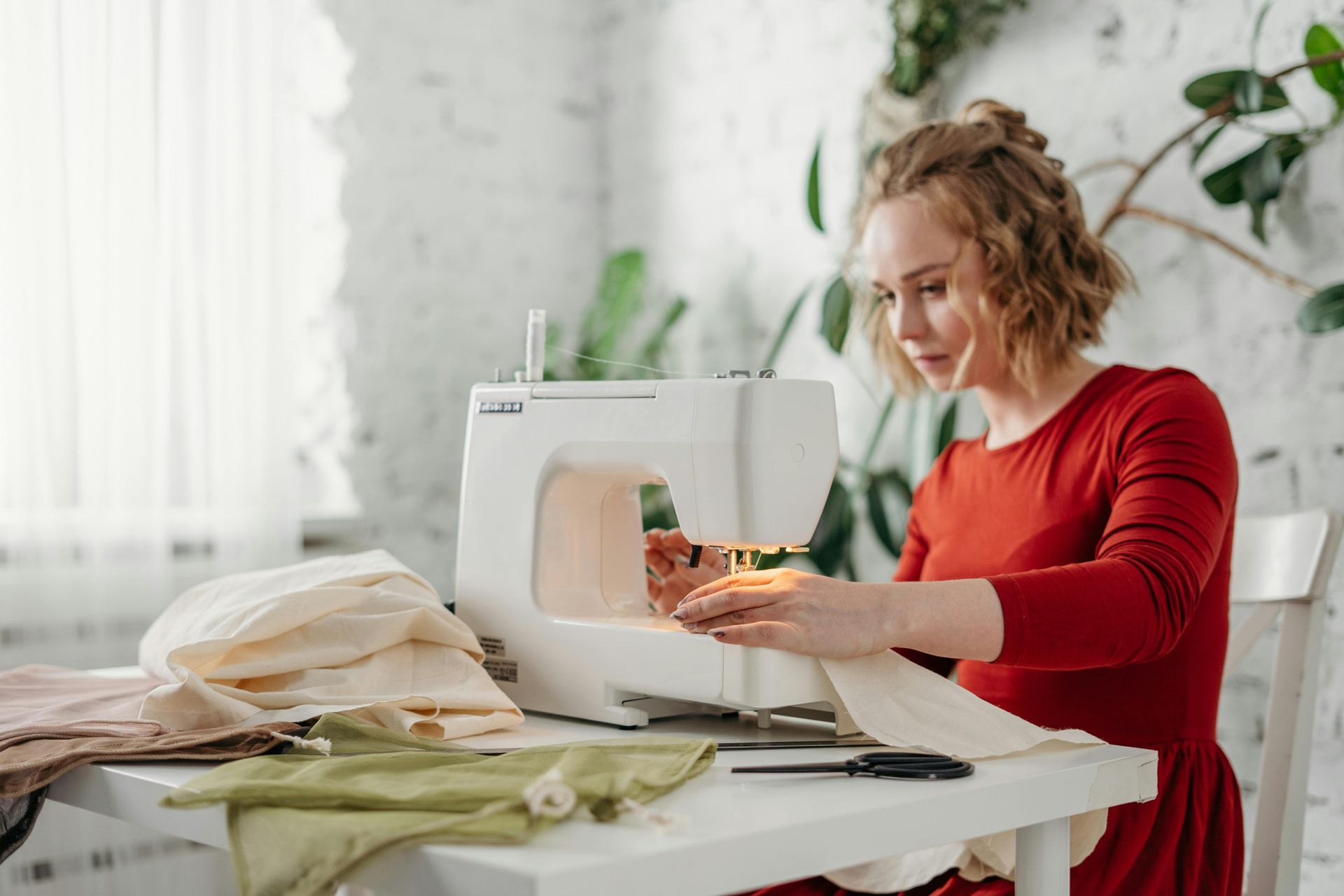 A woman is sitting at a table using a sewing machine.