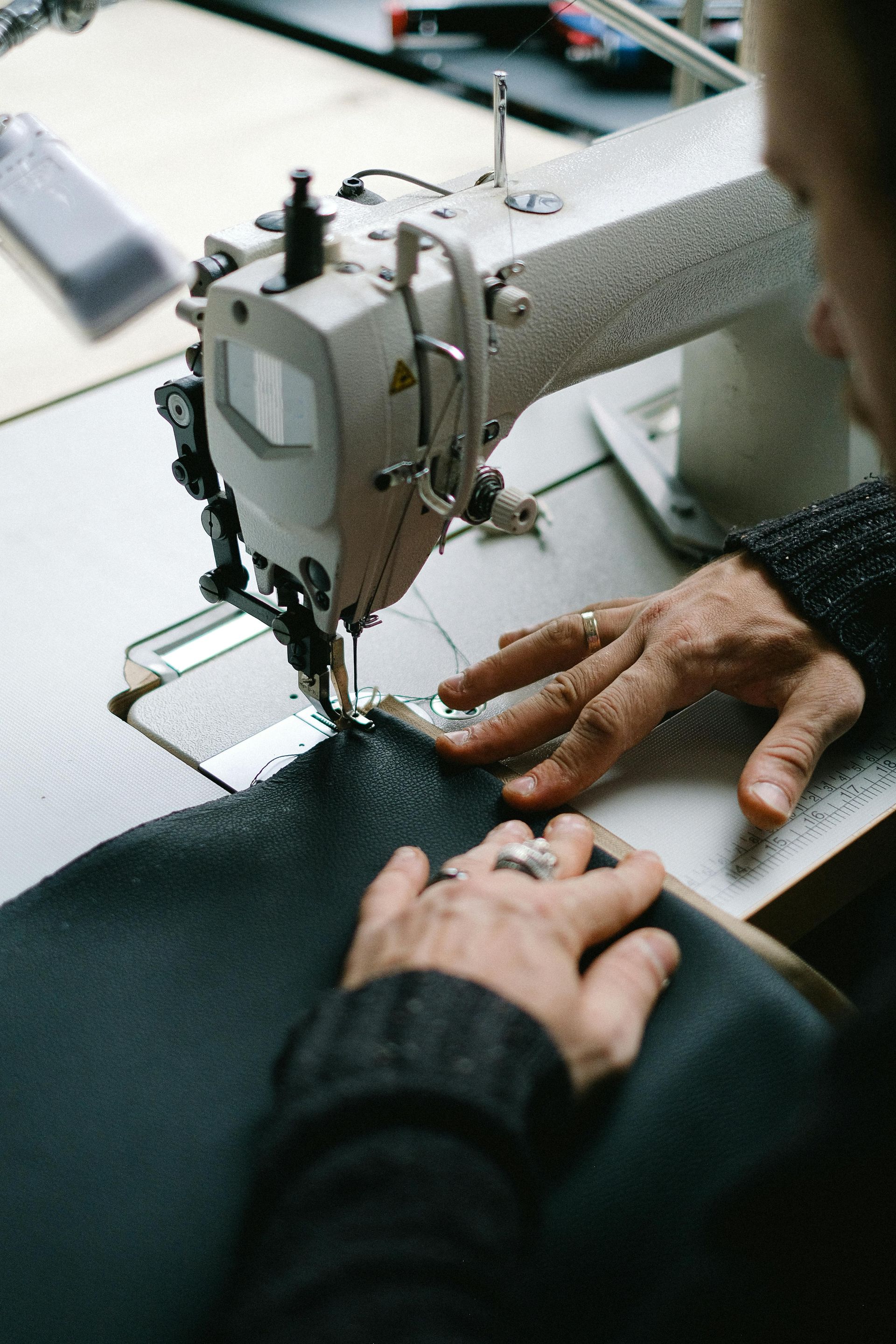 A person is using a sewing machine to sew a piece of fabric.