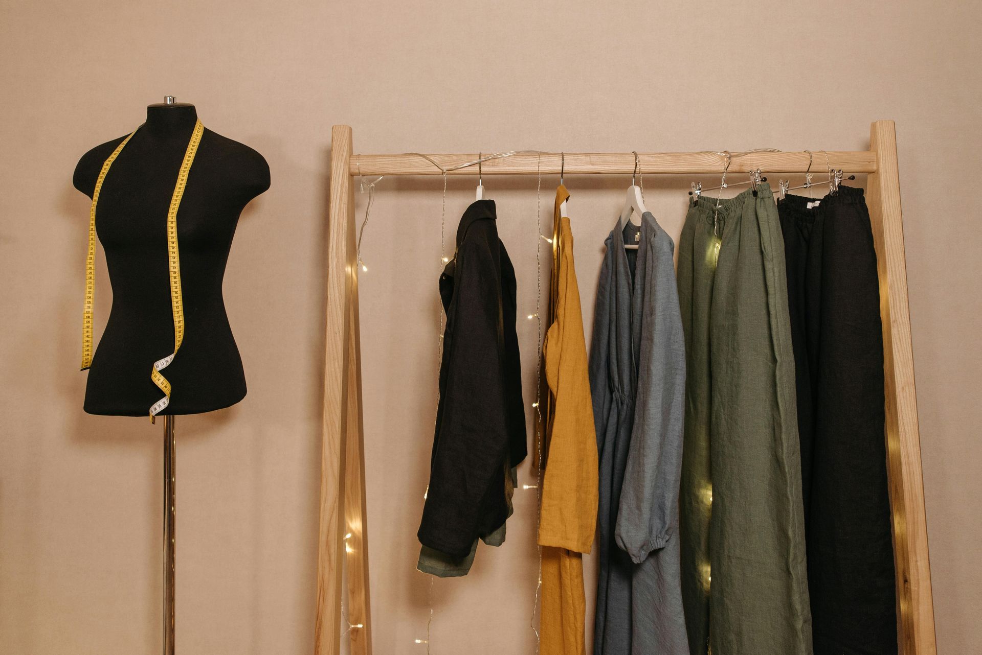 A mannequin is standing next to a wooden rack with clothes hanging on it.