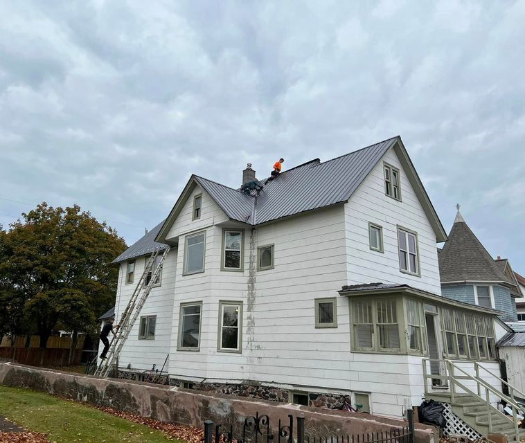 Gutter on a shingled roof with town buildings in the background