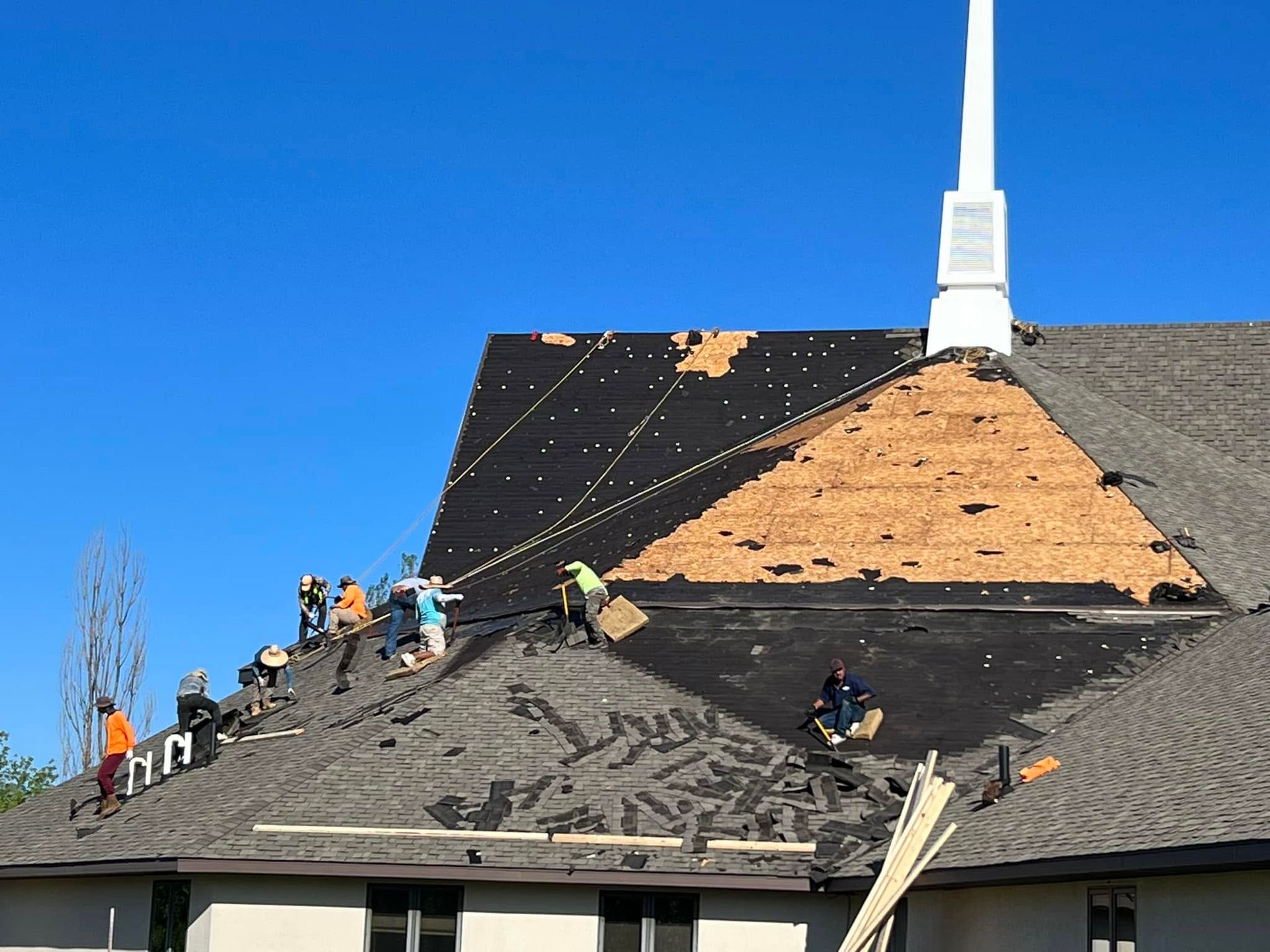 Worker installing asphalt shingles on a roof with a nail gun
