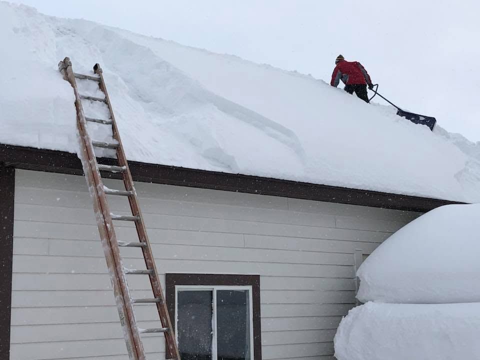 Person shoveling snow from a brick walkway with a black snow shovel