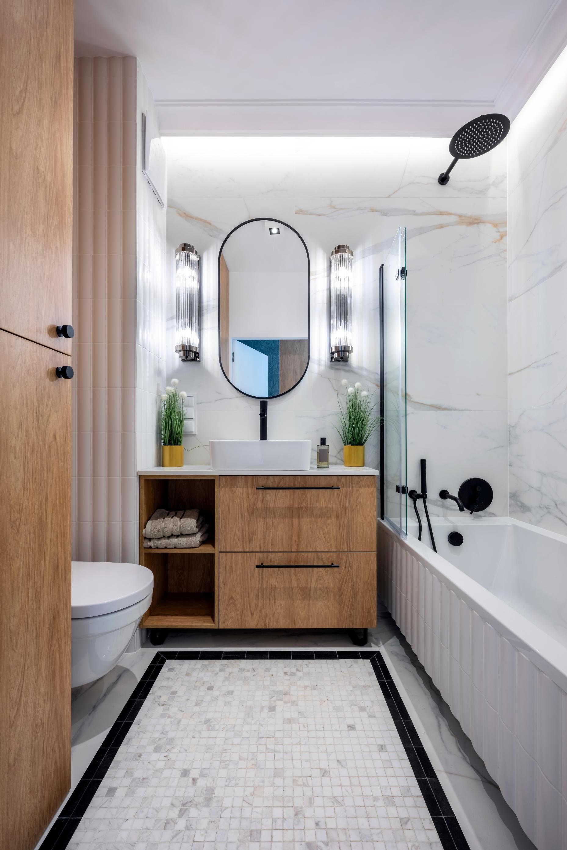 Modern bathroom with wood vanity, round mirror, white tub, black fixtures, and patterned rug