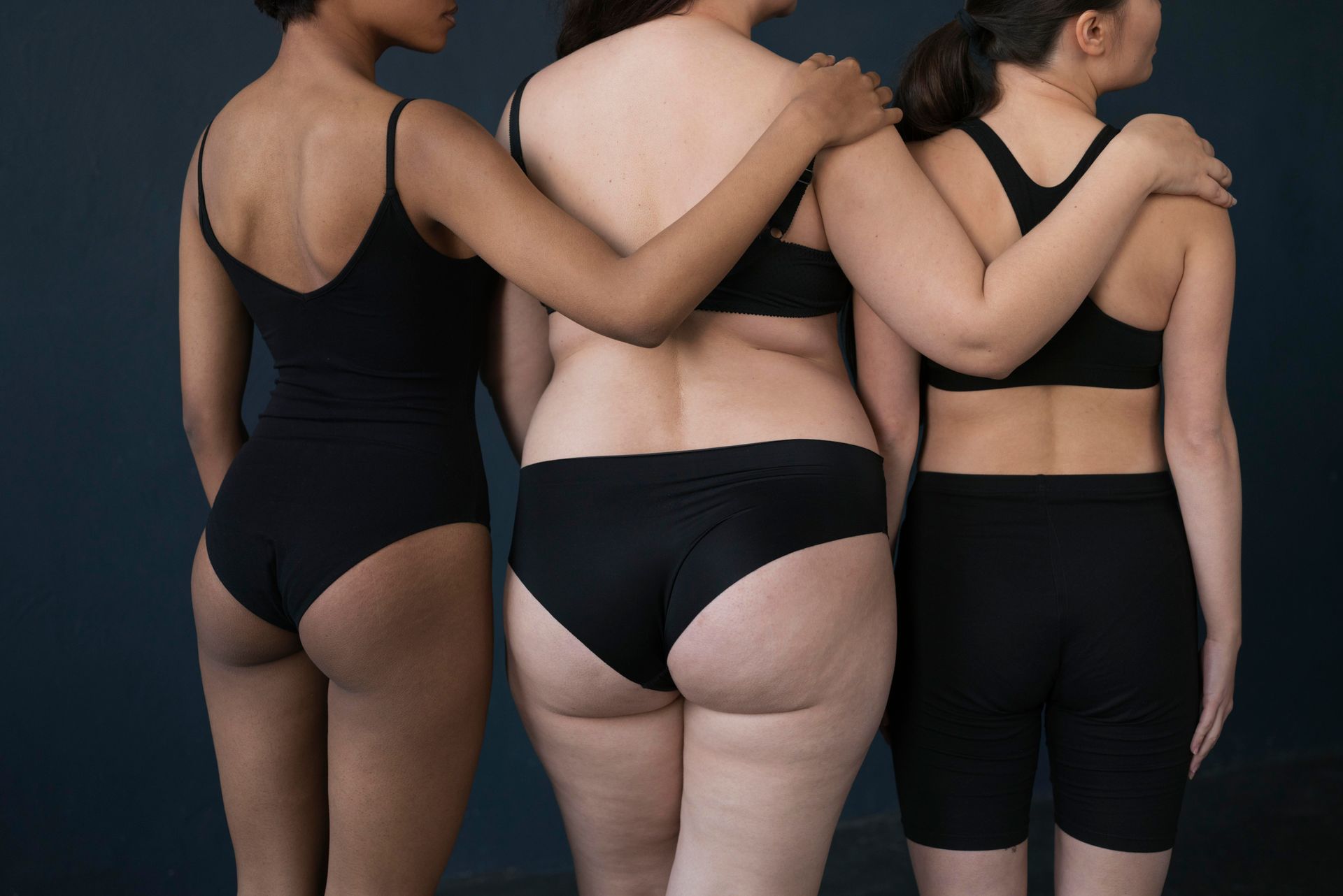Three women in black underwear are standing next to each other.