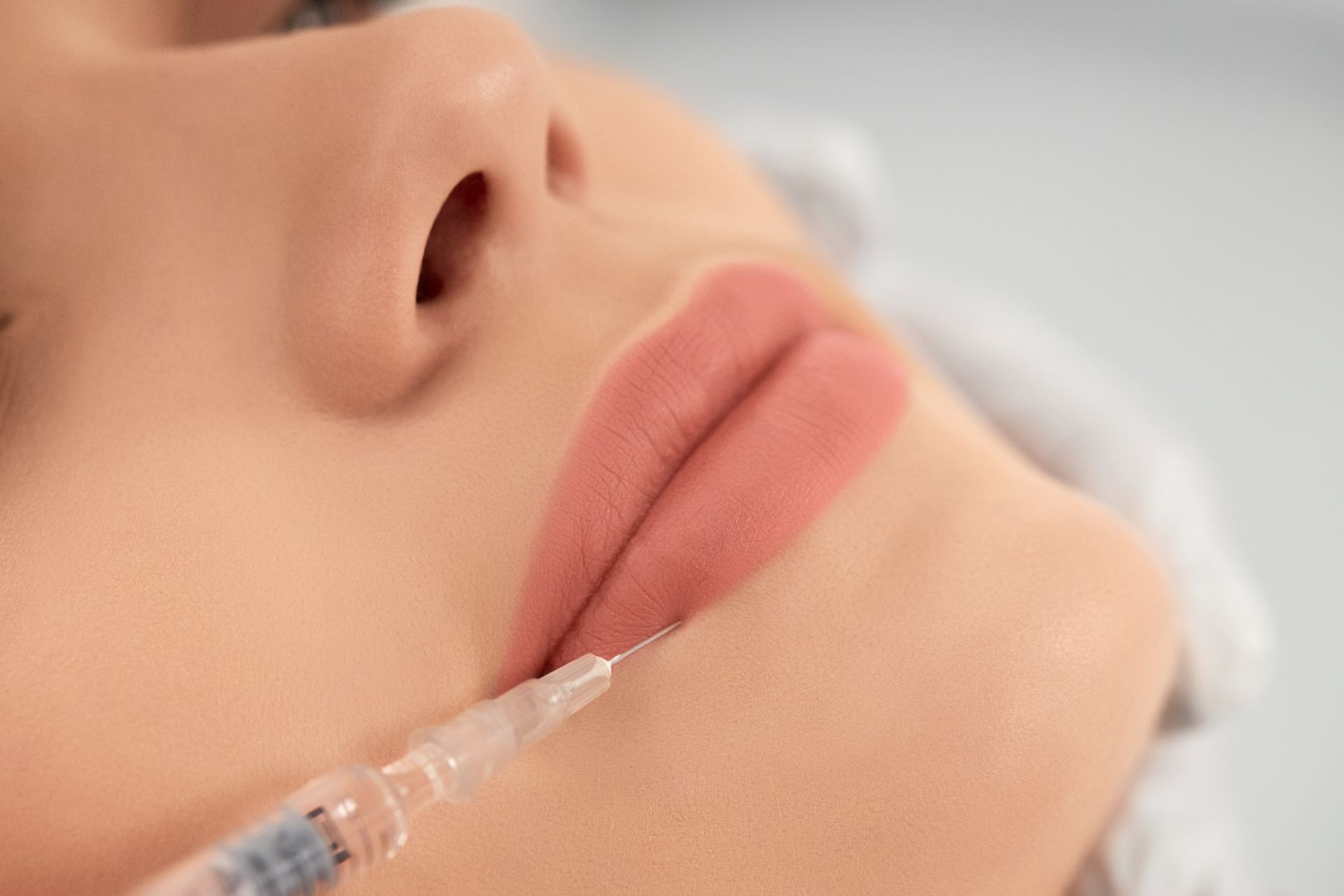 A woman is getting a filler injection on her lips.