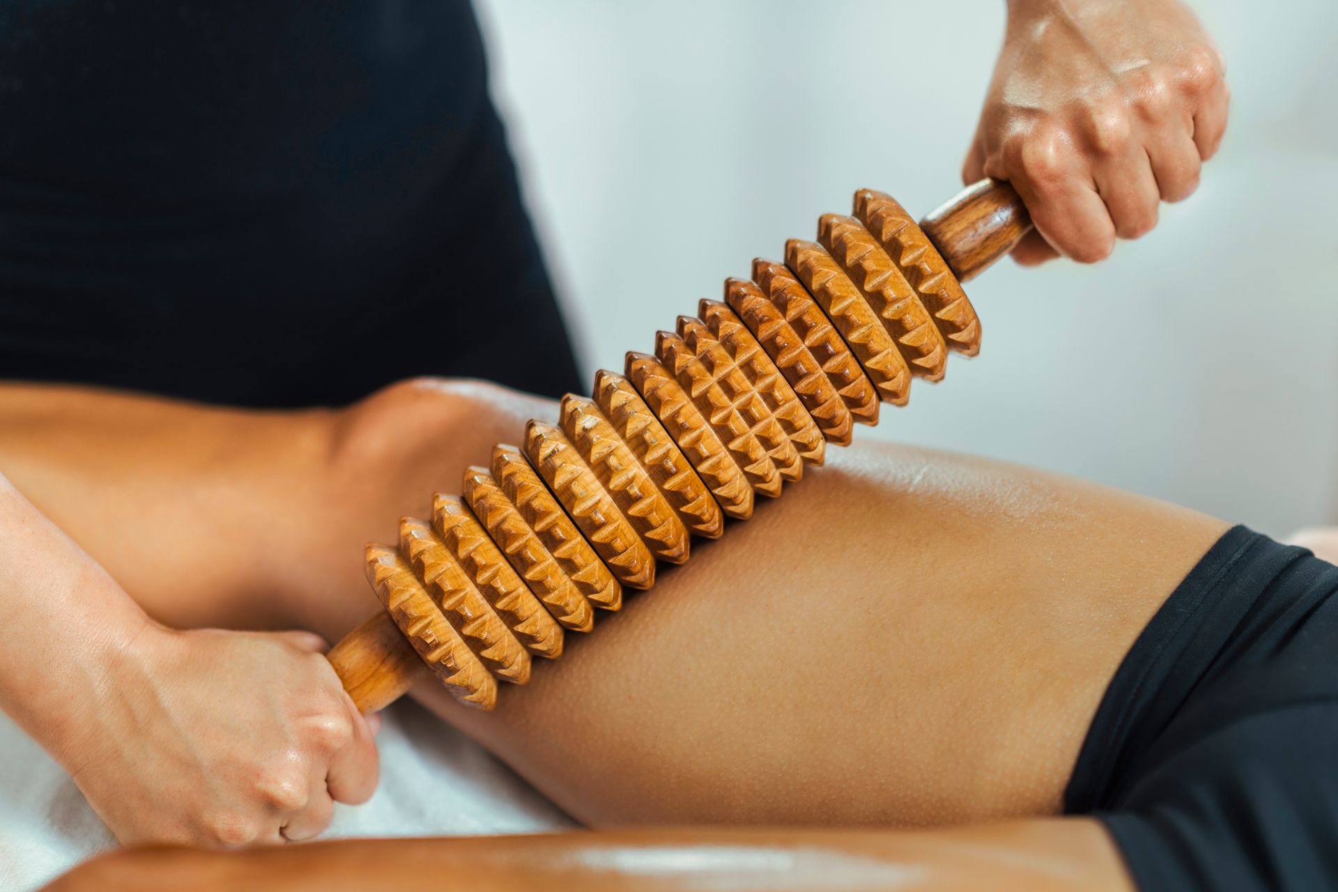 A woman is getting a massage with a wooden roller.