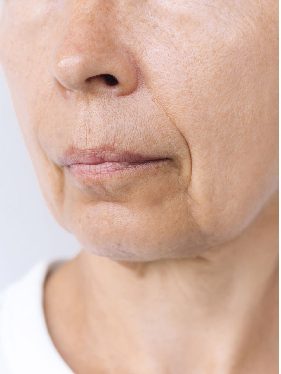 Close-up of an older person's face; showing wrinkles around the mouth and a soft, neutral complexion.