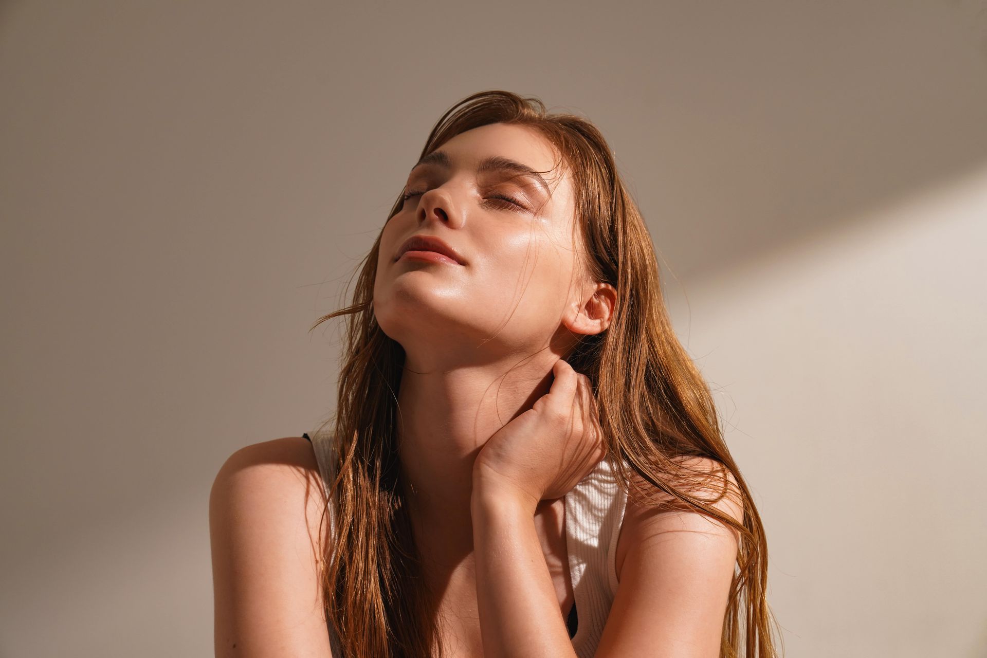 A woman with wet hair is looking up at the sun.