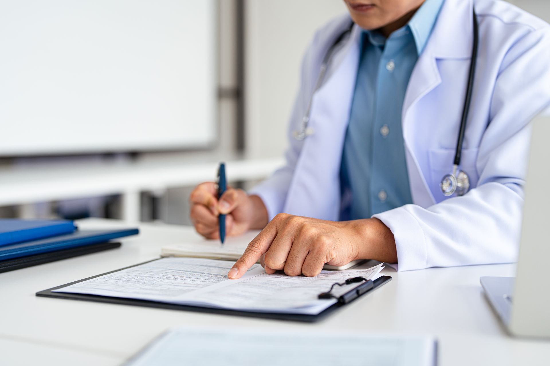 Doctor writing notes on a clipboard in a bright clinic office