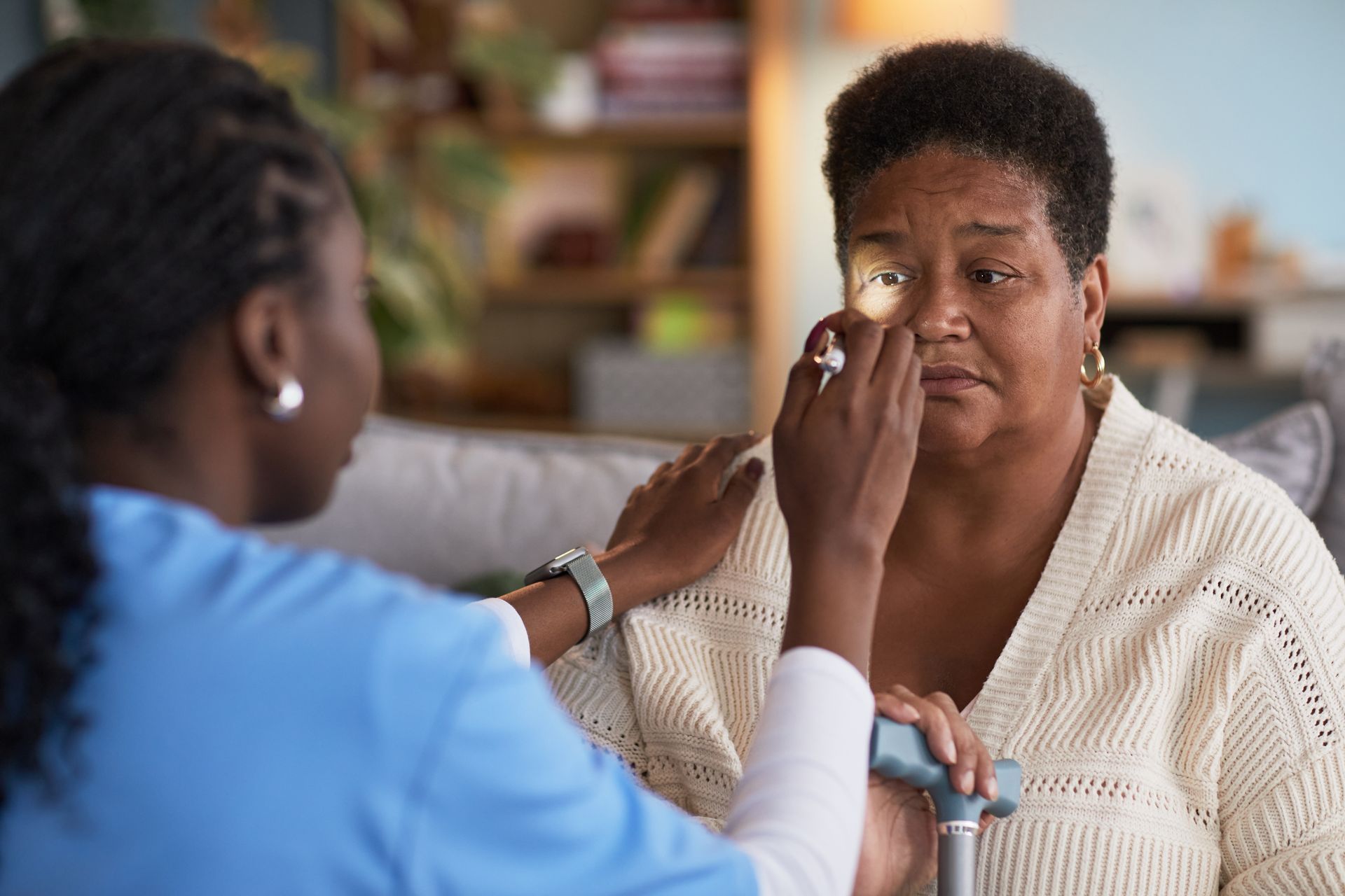 Clinician checking a patient’s eye in a bright living room