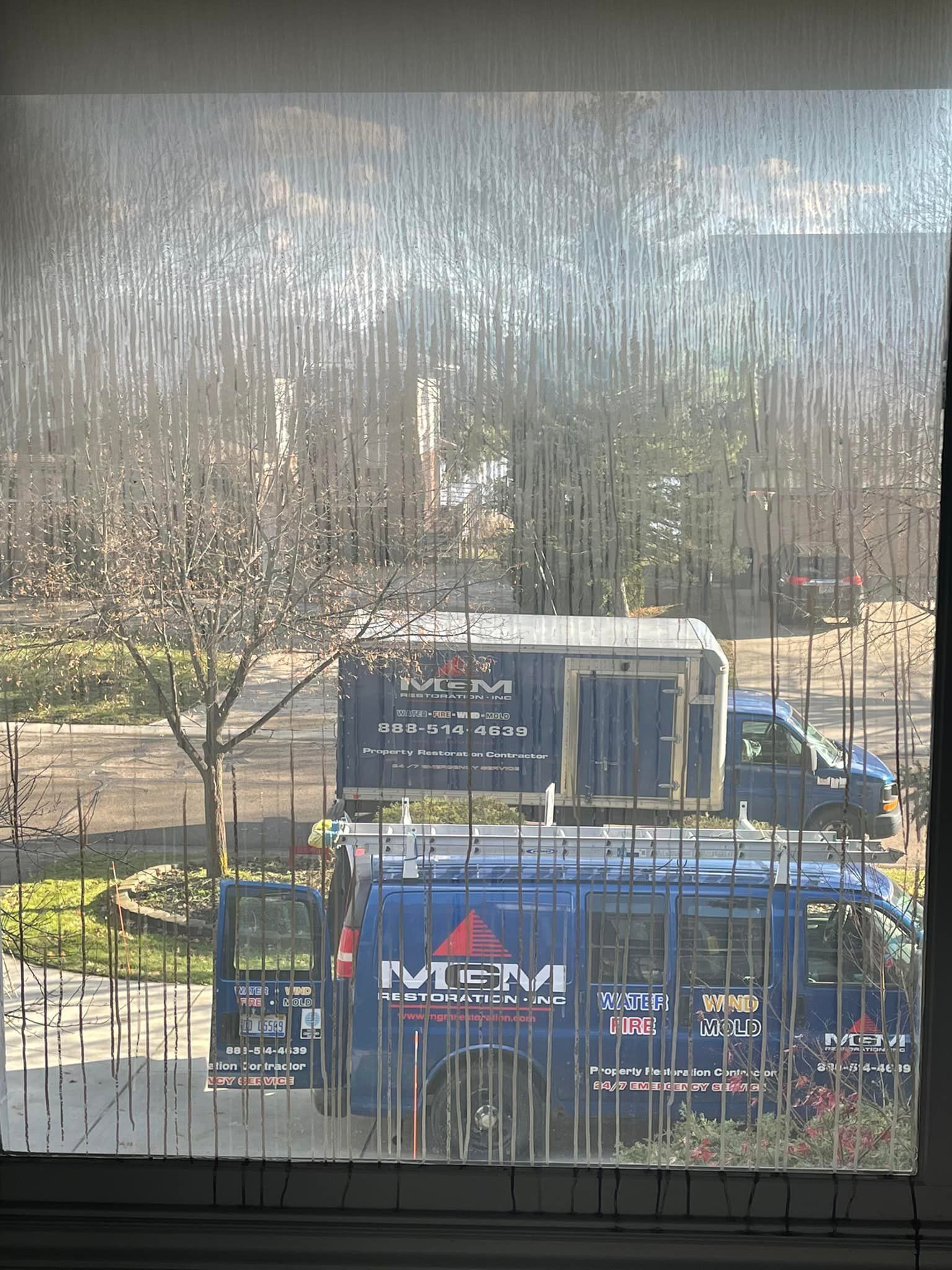 A blue van with the word miami on the side is parked in front of a window.