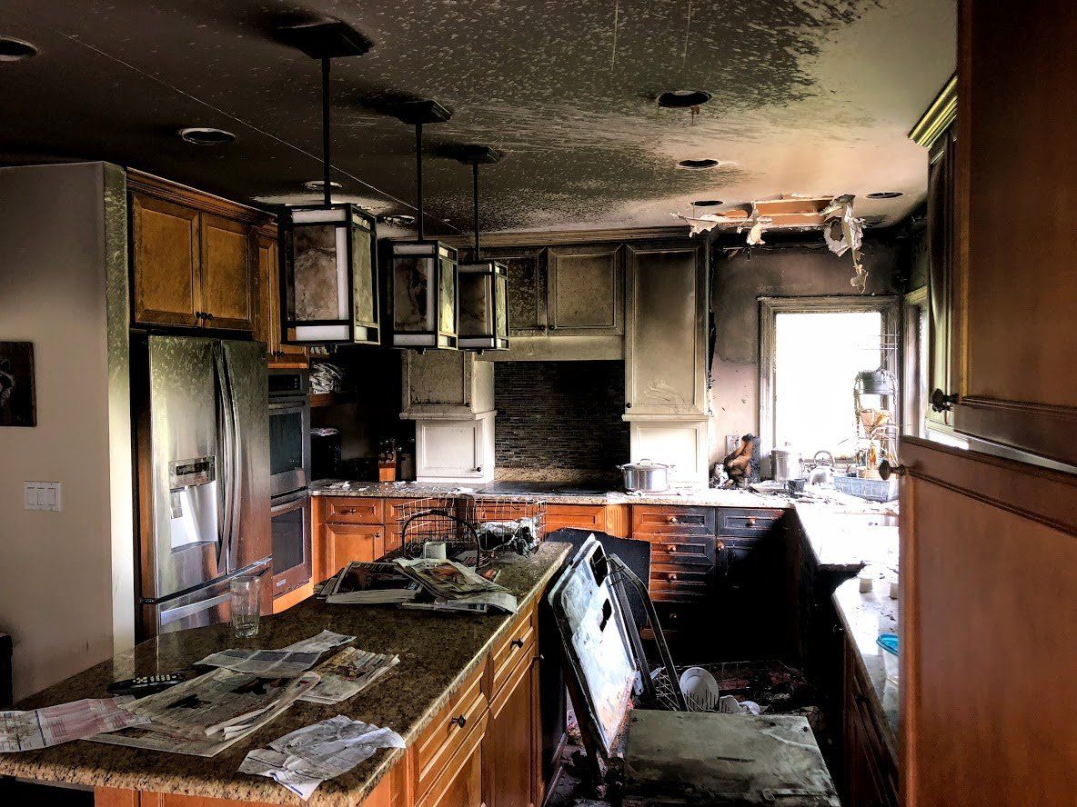 A kitchen with a ceiling that has been damaged by a fire.