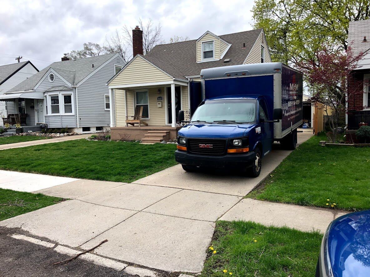 A blue gmc van is parked in front of a house.
