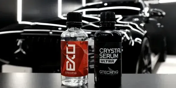 Two GTCHG beverage bottles on a car engine background, one red and one black crystal serum bottle.