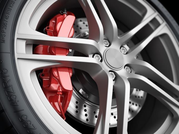 Close-up of a silver alloy wheel with a red brake caliper and ventilated brake disc.