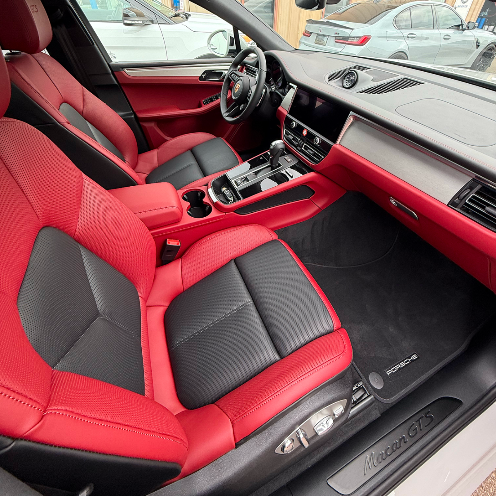 Red-and-black car interior with bucket seats, dashboard, and steering wheel visible.