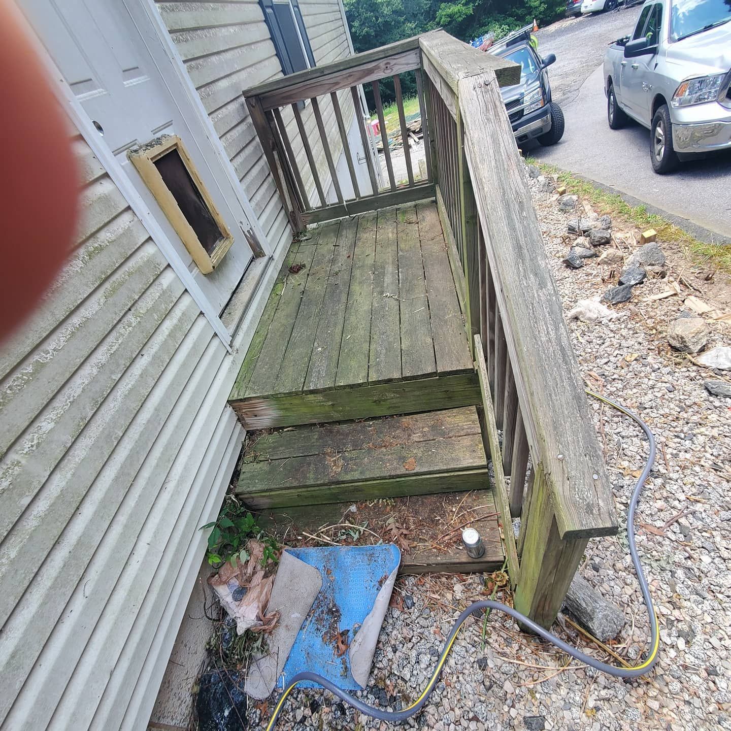 Wooden porch with steps, weathered wood, handrail, attached to a building's side, exterior.
