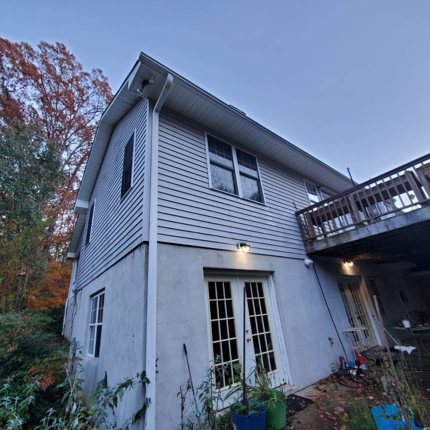 Two-story house with gray siding, white trim, and a wooden deck. The base is light gray with French doors.