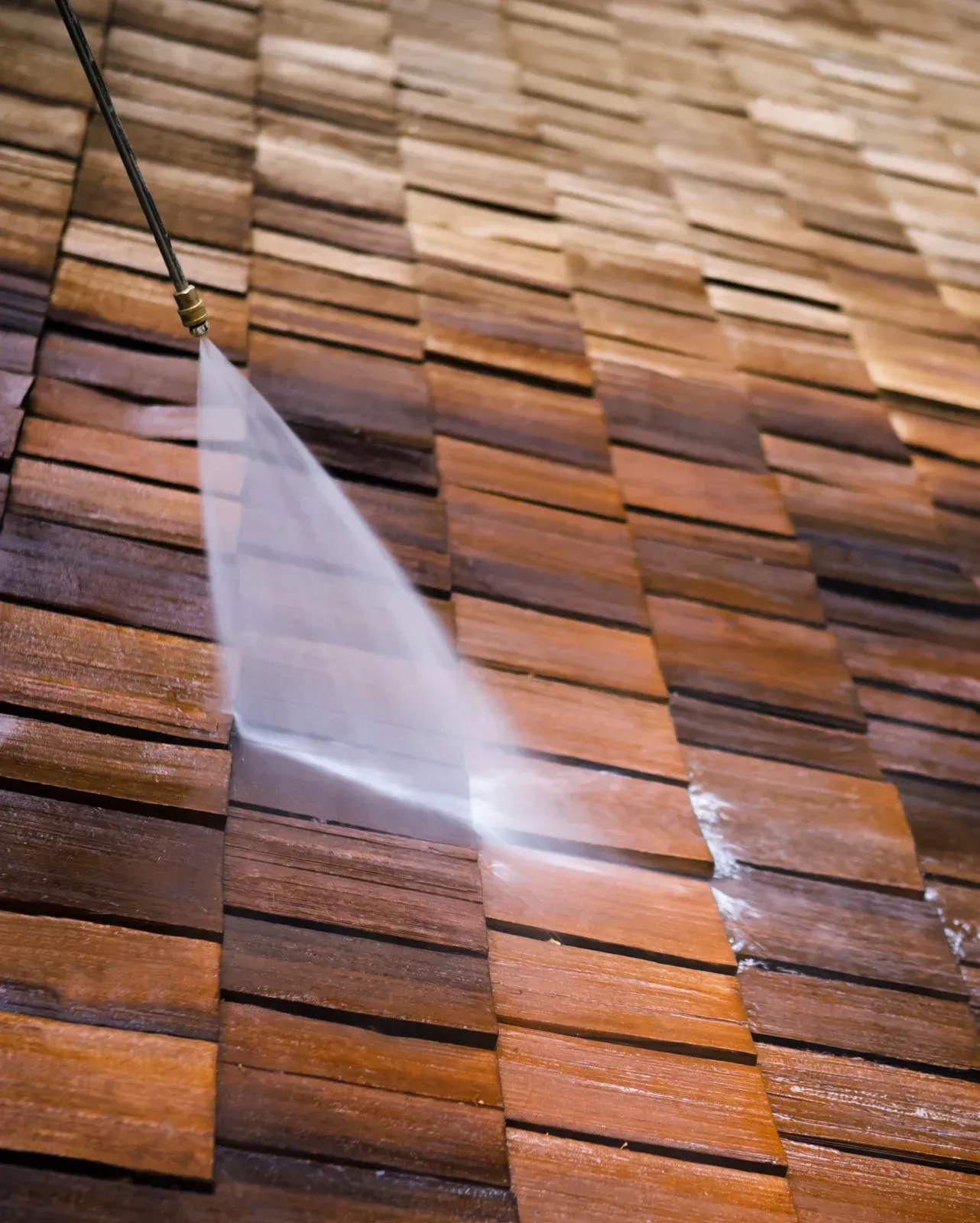 Pressure washing a wood shingle roof, cleaning off dirt and debris.
