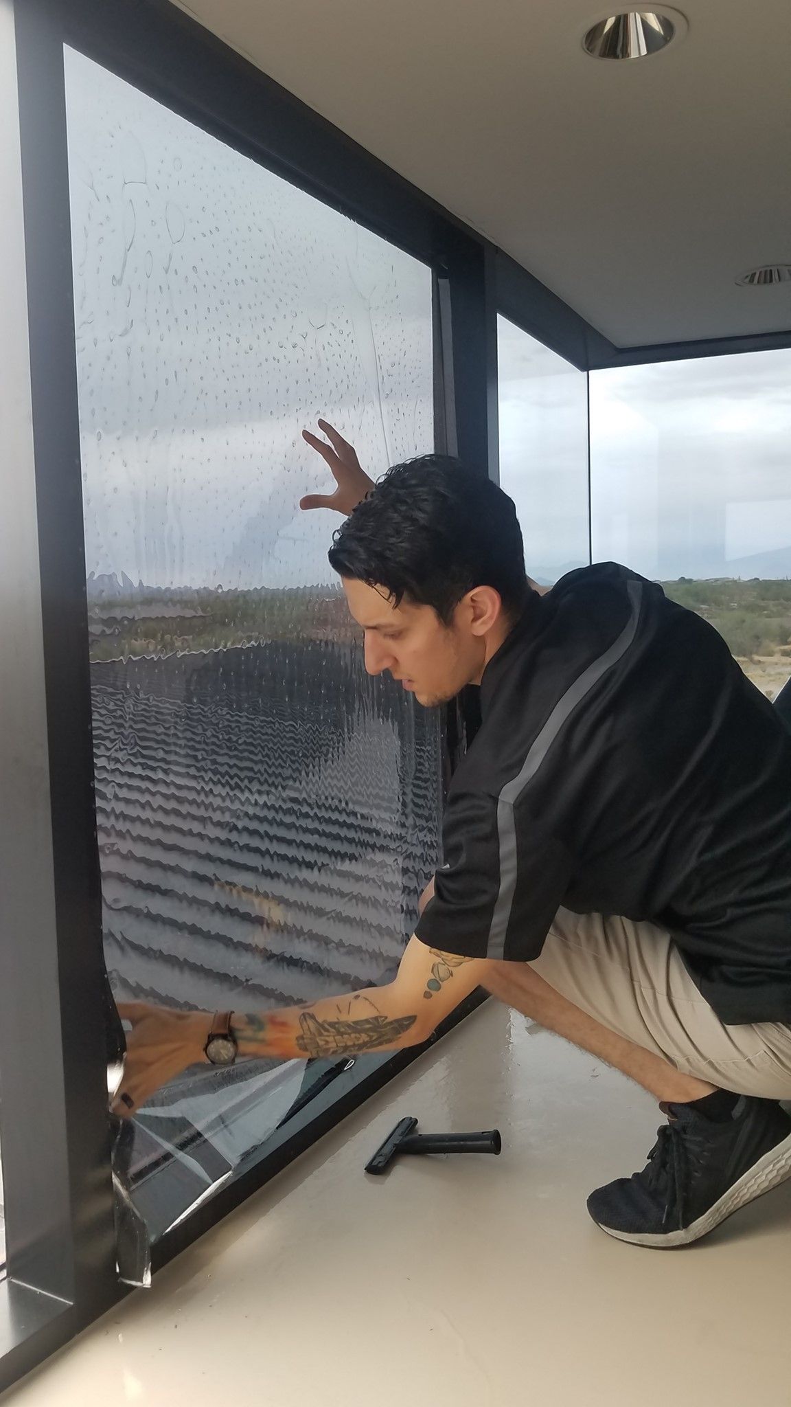 Two men are installing window tinting on a window.