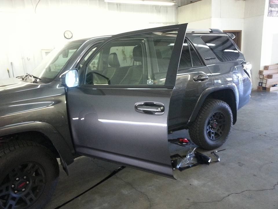 A gray suv is parked in a garage with its doors open.