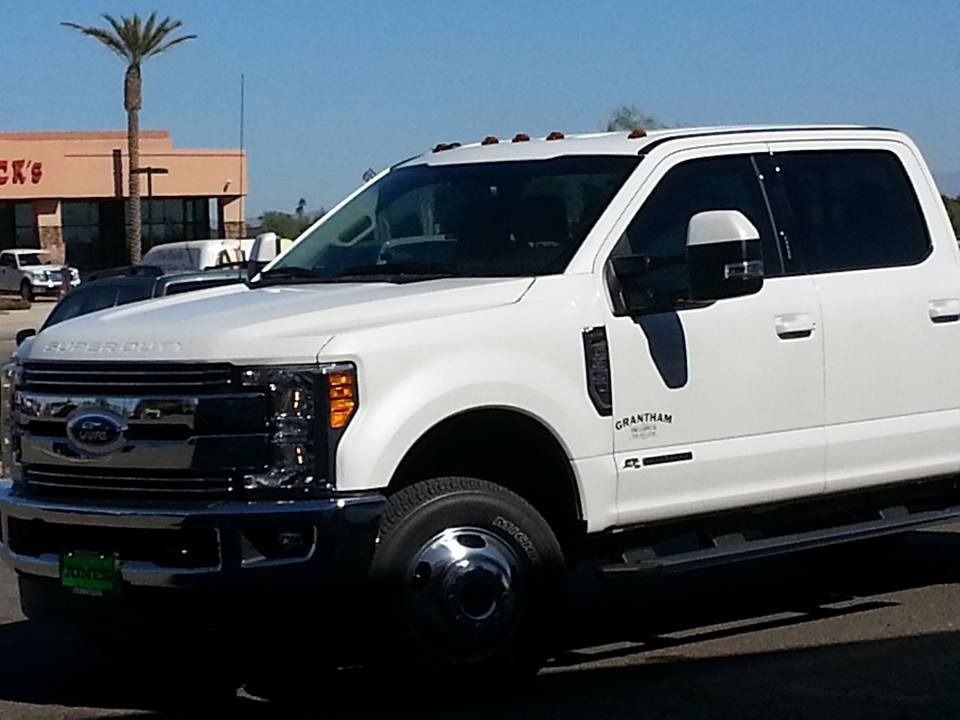 A white ford truck is parked in front of a store