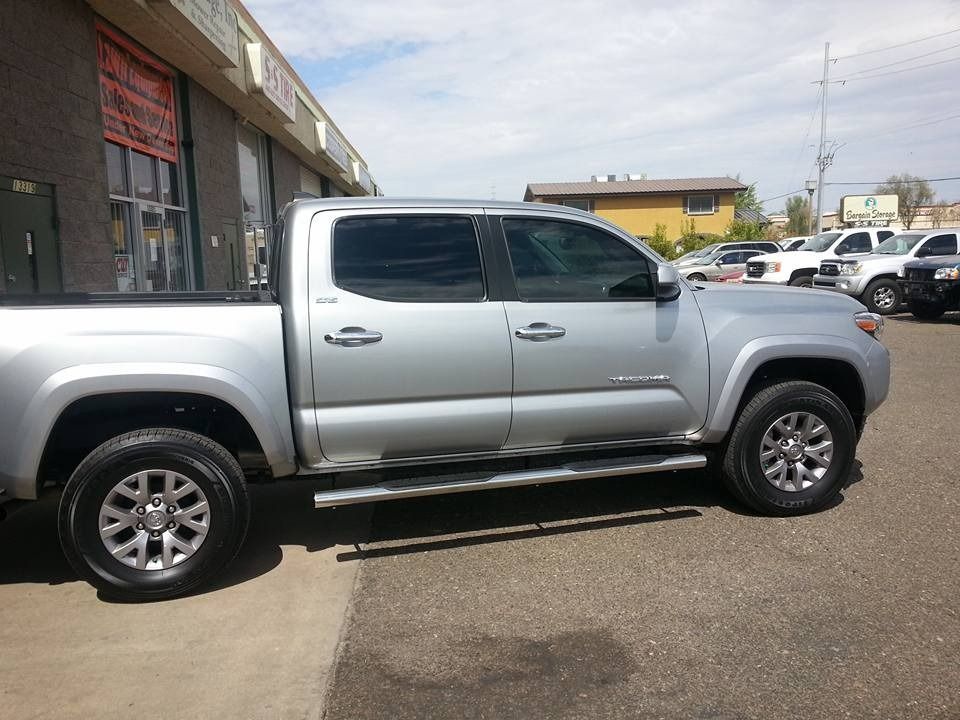 A silver truck is parked in front of a building