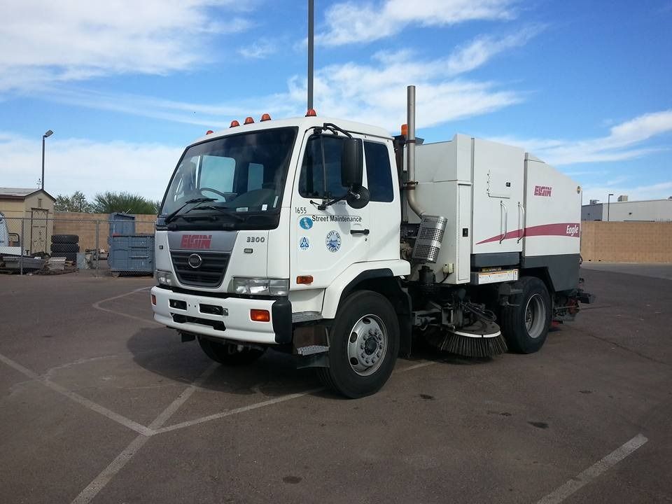 A white street sweeper truck is parked in a parking lot