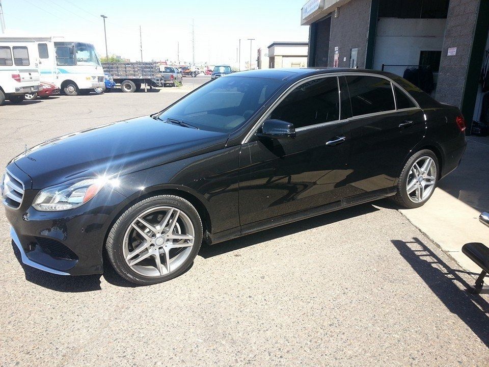 A black mercedes benz is parked in a parking lot