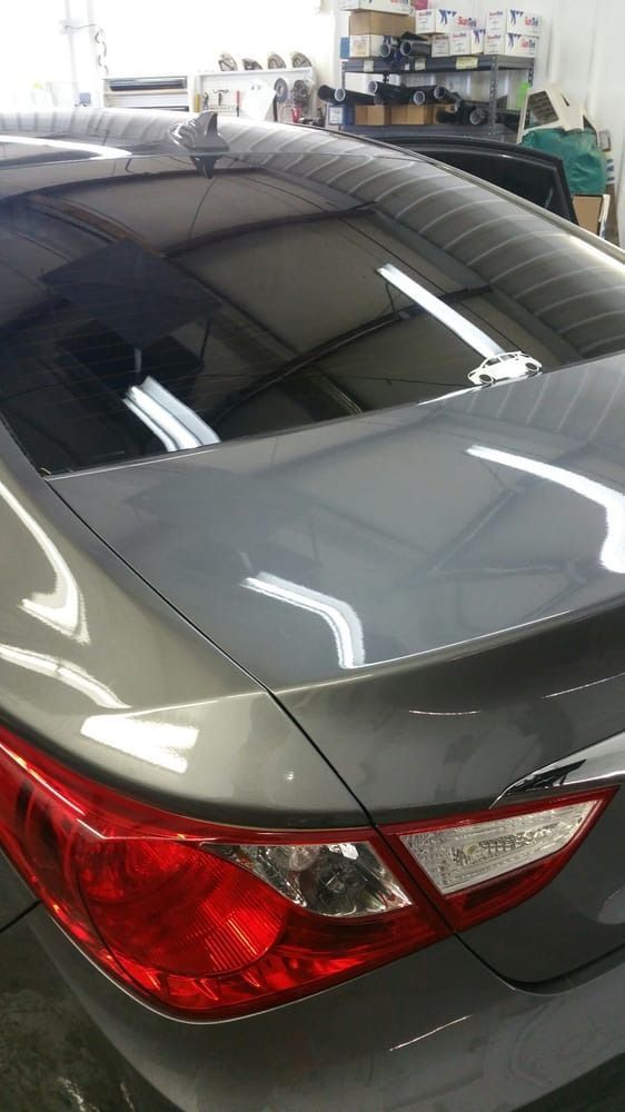 A gray car with a red tail light is parked in a garage.