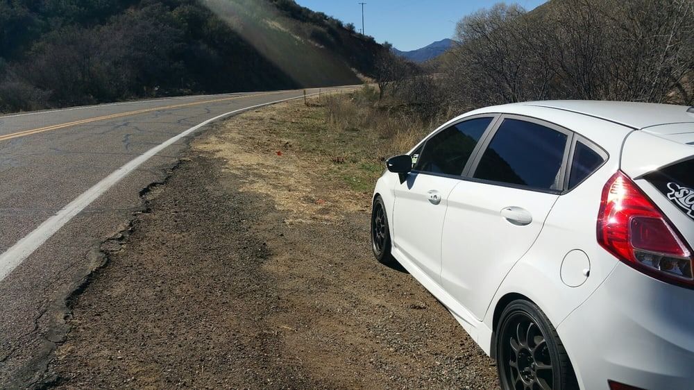 A white car is parked on the side of the road