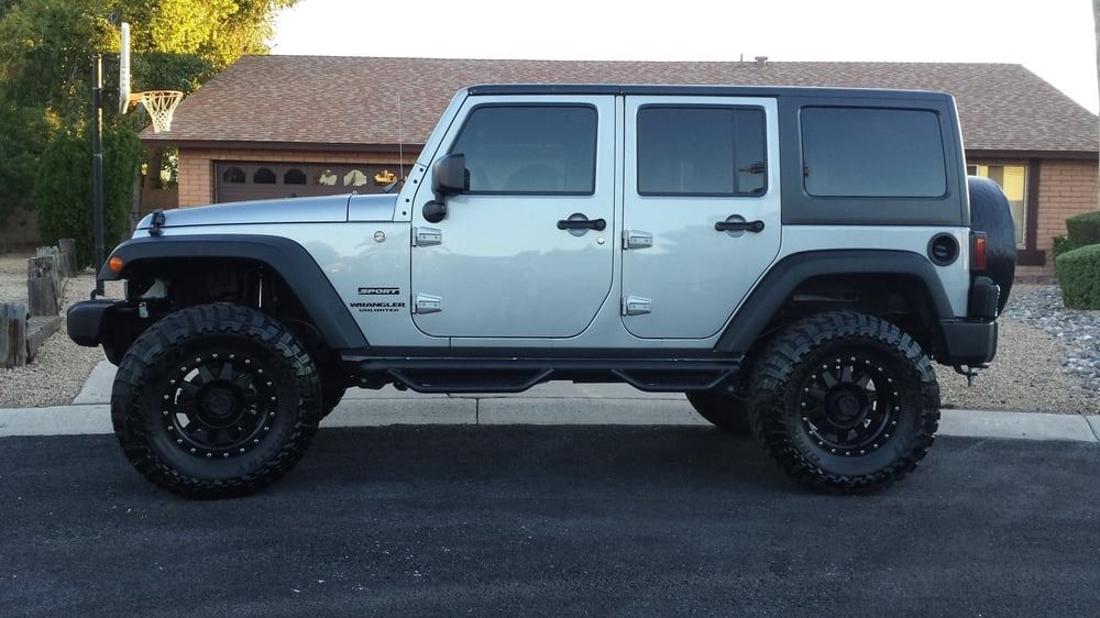 A silver jeep is parked in front of a house.