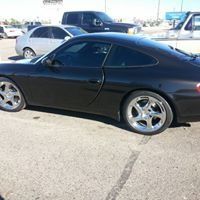 A black porsche 911 is parked in a parking lot.