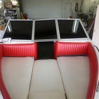 The inside of a boat with red and white seats and a black windshield.