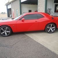 A red dodge challenger is parked in front of a garage.