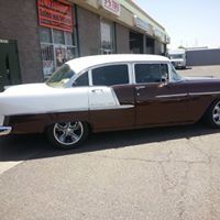 A brown and white car is parked in front of a building.