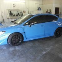 A blue subaru wrx sti is parked in a garage.