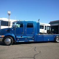 A blue semi truck with a trailer attached to it is parked in a parking lot.