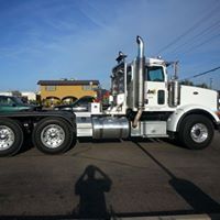 A white semi truck is parked on the side of the road.