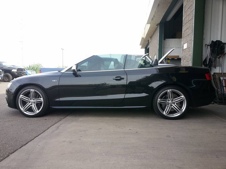 A black convertible is parked in a parking lot with the top down.