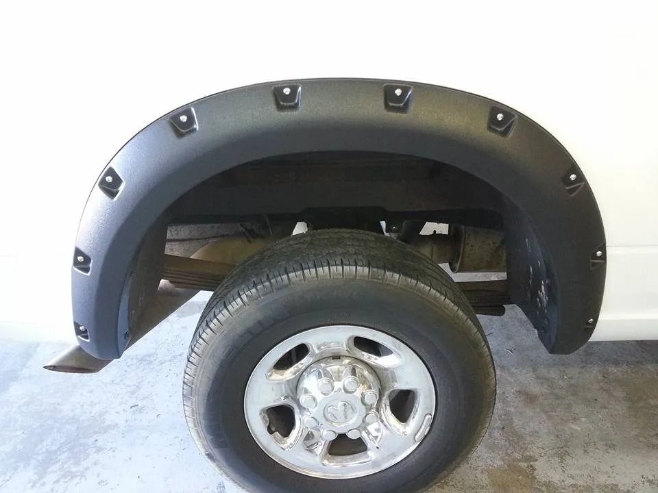 A white truck with black fender flares and a silver tire