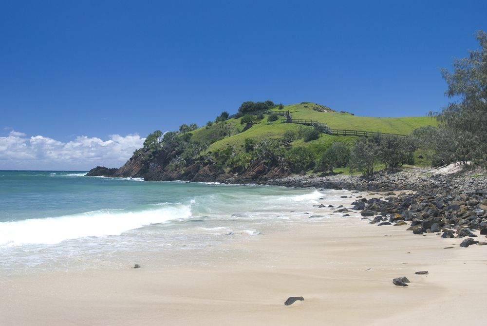 A Beach With a Hill in the Background and a Blue Sky — Killiby & Co Roofing Pty Ltd in Cabarita Beach, NSW